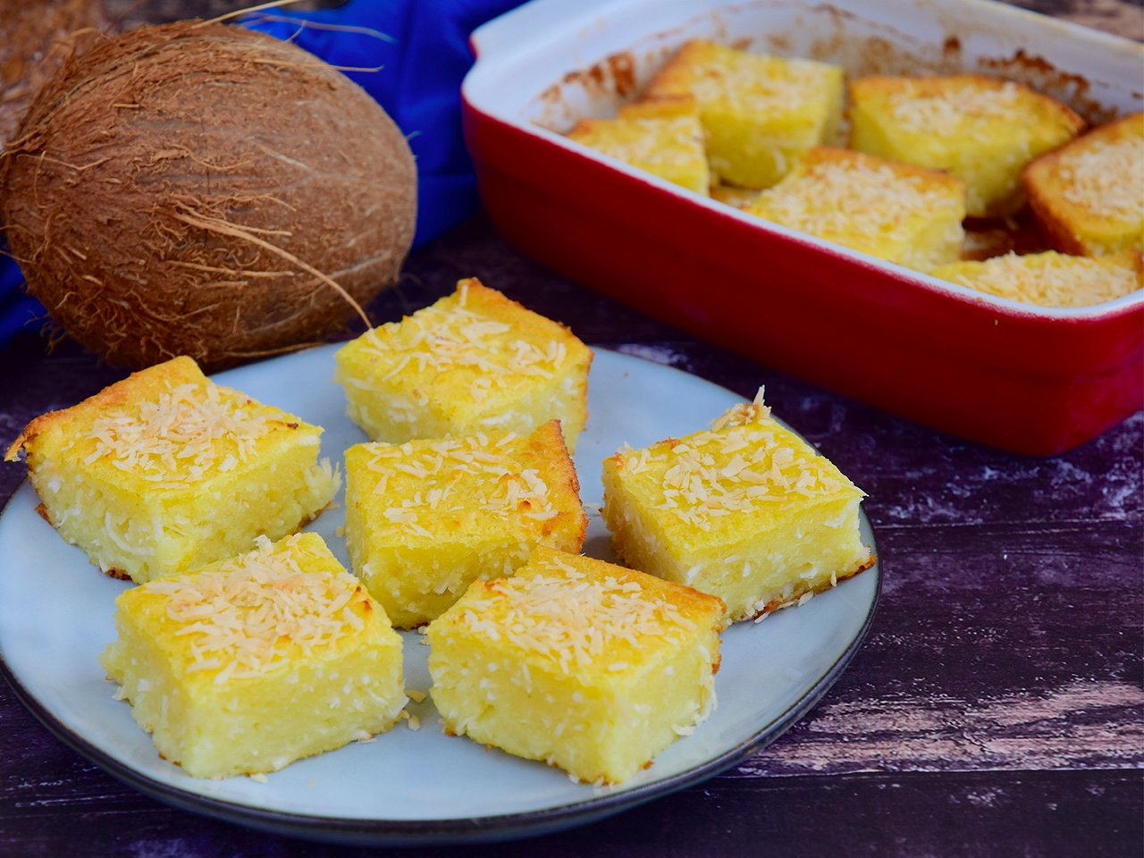 Cassava cake on a plate with coconuts in the background