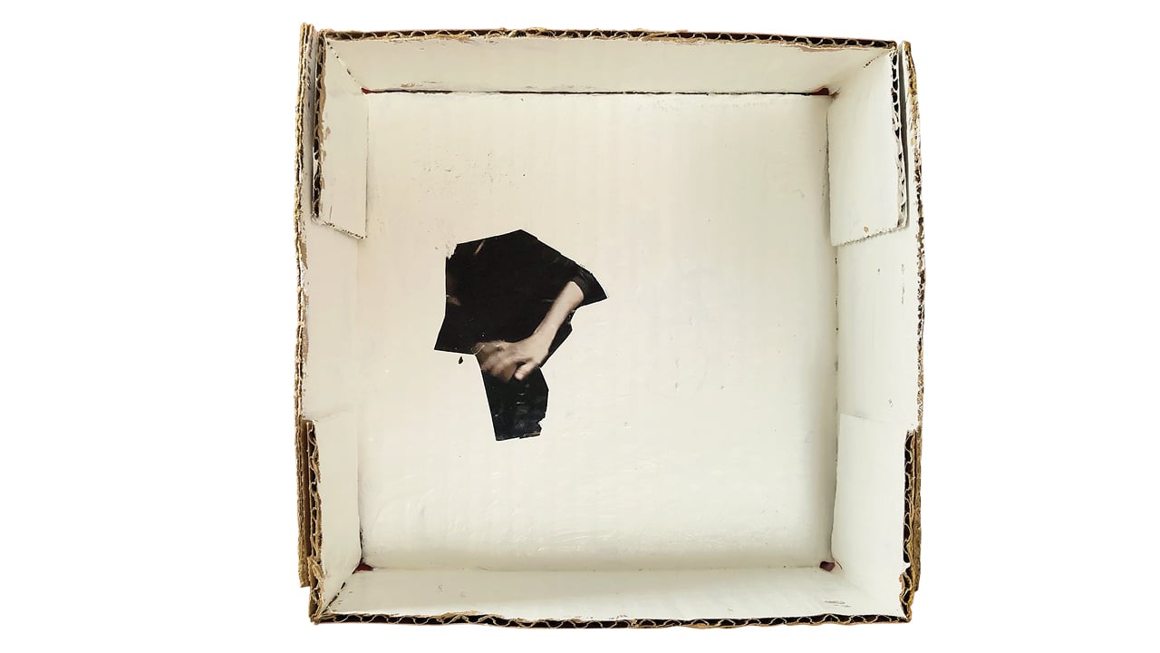 A photo illustration of an empty box with a hole at the bottom through which you can see a woman's hand