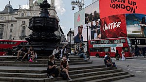 People sitting on the the steps of a statue in Trafalgar square, London, U.K.