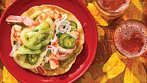 A plate with a green tomato and shrimp tostada on top