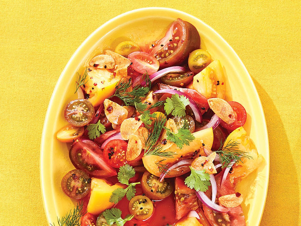 A plate of heirloom tomato salad against a yellow background