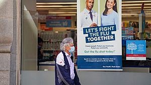 A pedestrian walks by a sign in a store window encouraging people to receive a seasonal flu shot in Toronto on Tuesday, October 19, 2021. (Photo: The Canadian Press / Evan Buhler)