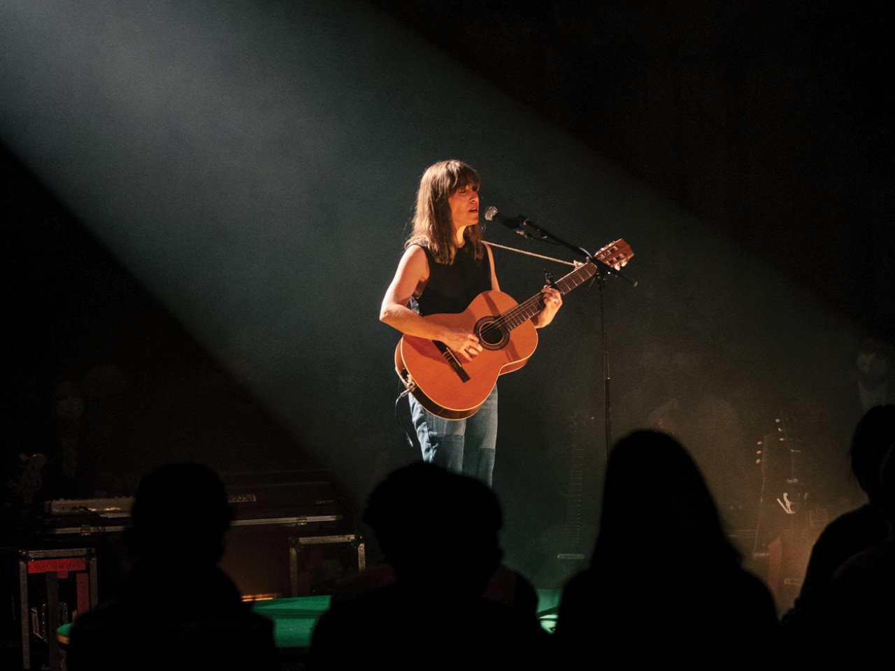 Leslie Feist, holding a guitar, sings on stage
