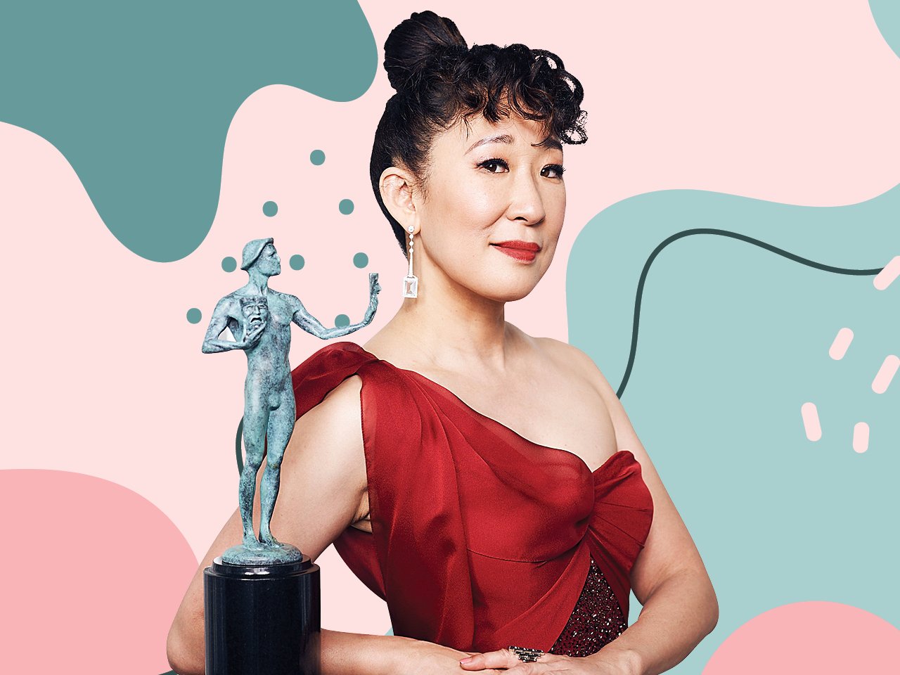 Image of Sandra Oh in a red dress posing next to an award