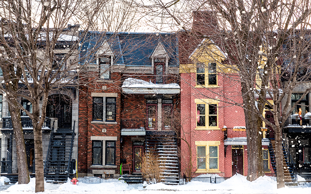 Montreal row houses viewed from the front in winter, with snow falling and bare trees