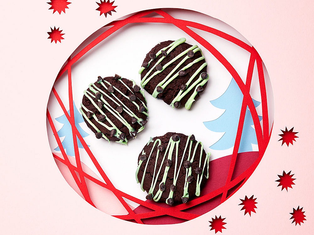 A plate with three mint chip cookies—dark brown and drizzled with a chocolate drizzle