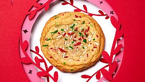 a brown butter holiday confetti cookie with red and green sprinkles in the centre of a cut-out paper ornament