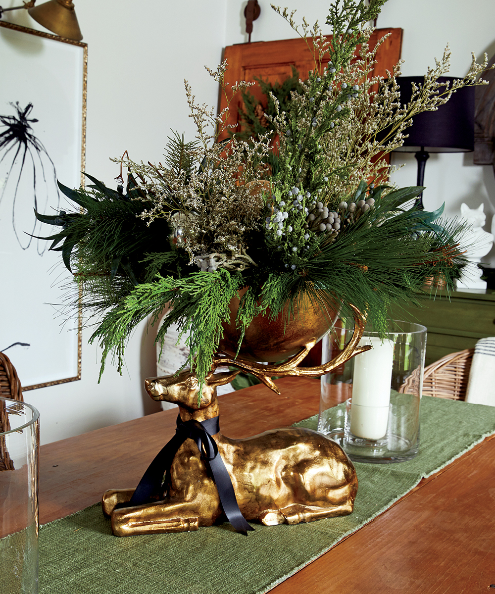 A bronze stag centrepiece on a green table runner on a brown wood table