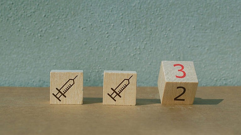 Three wood blocks showing, for the first two, a syringe, and the third, the number two turning to the number 3