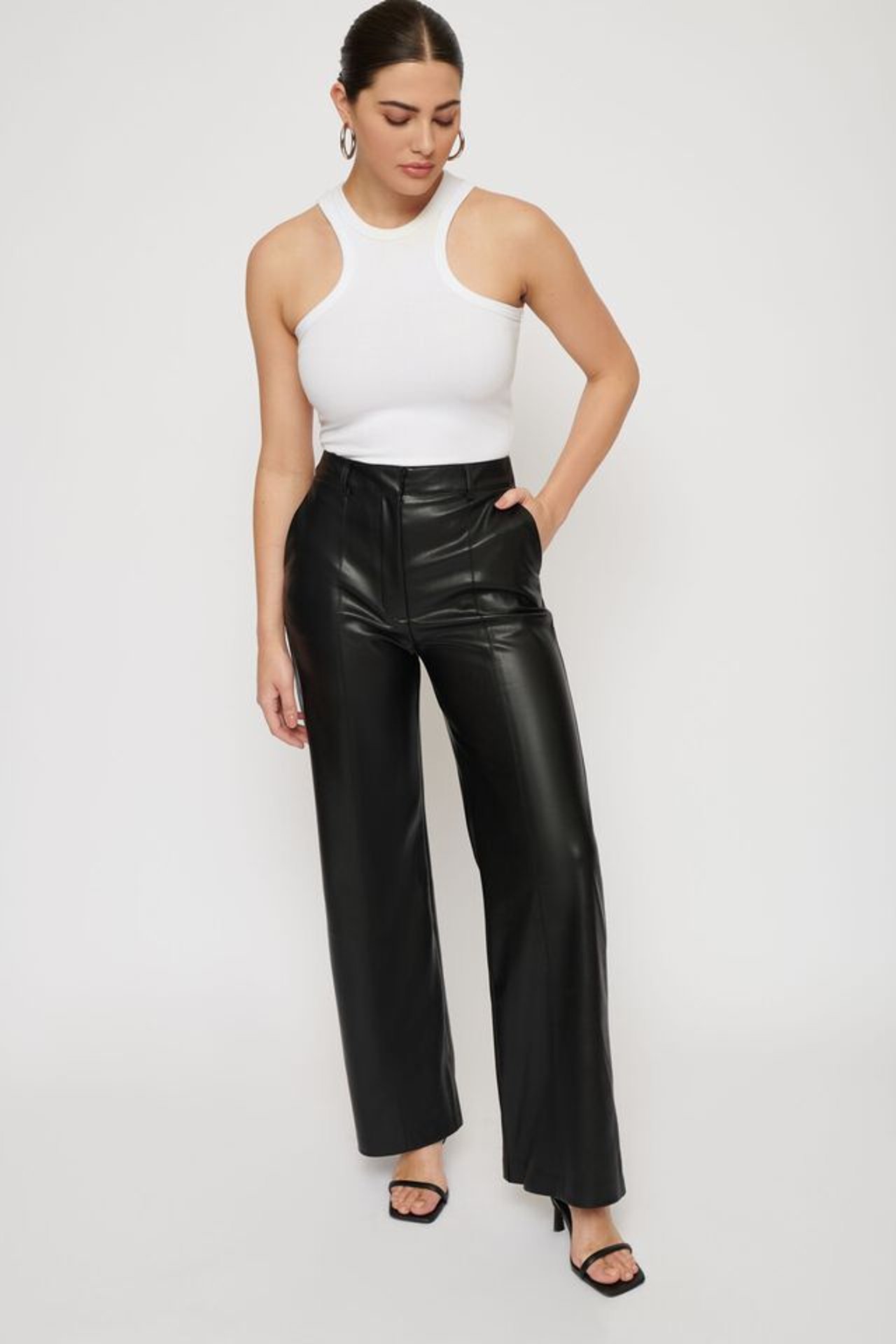 Woman in white top and black flare leather pants. 