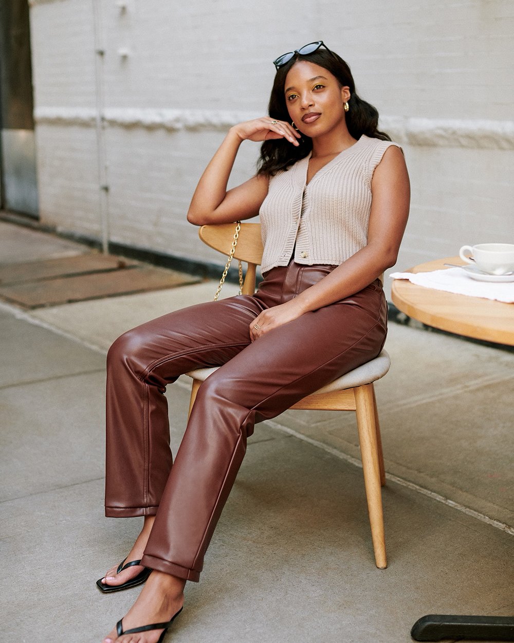 A woman sitting in a chair wearing a pair of brown faux-leather pants from Abercrombie & Fitch for a round-up of leather pants.