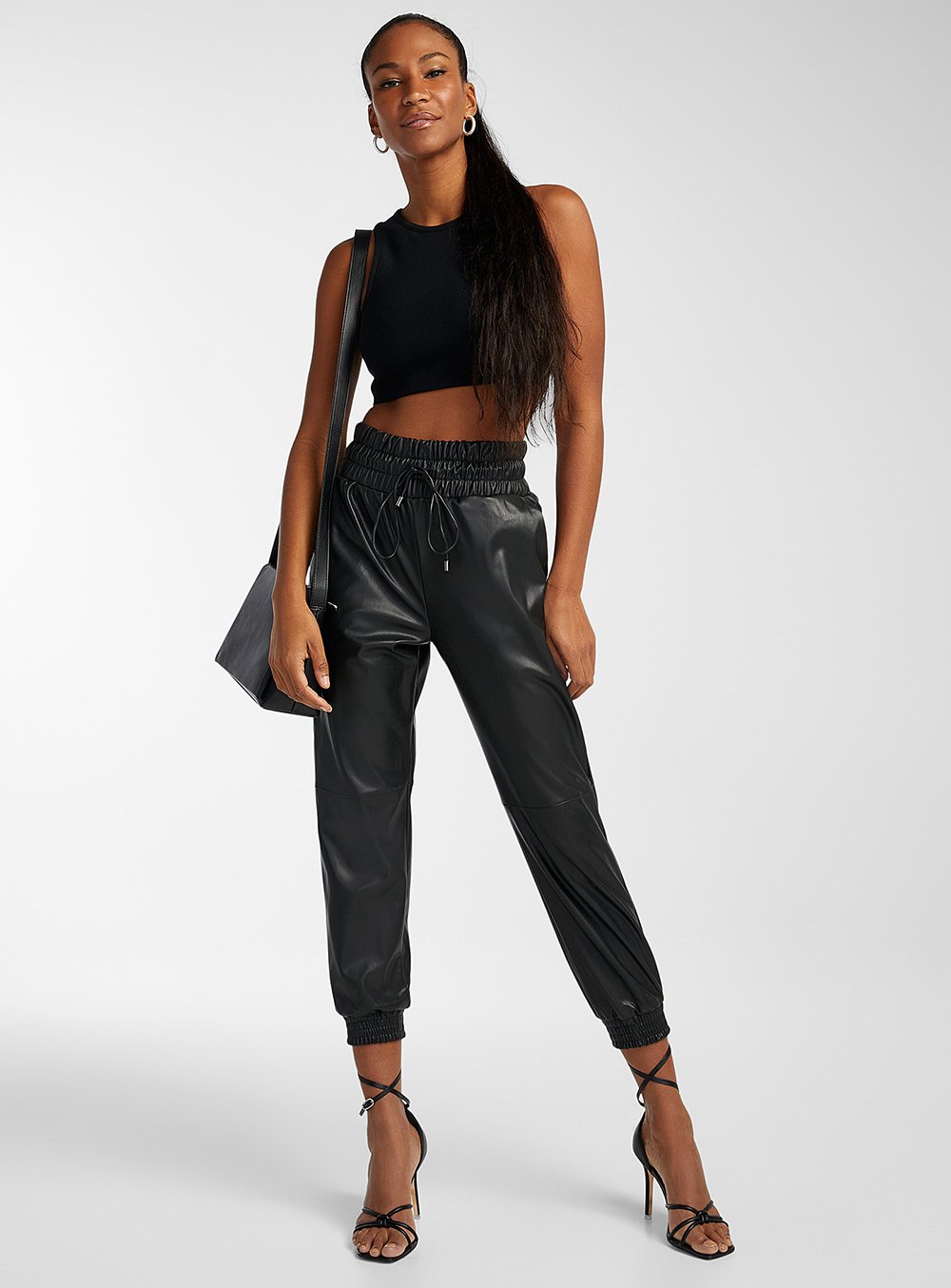 A model wearing faux-leather cuffed joggers for a round-up of leather pants.