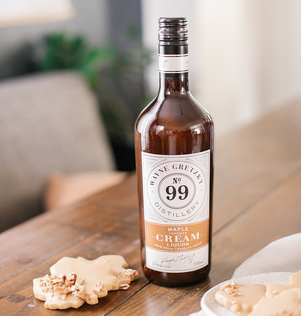 A bottle of Wayne Gretzky Distillery Maple Cream on a wood table with cookies