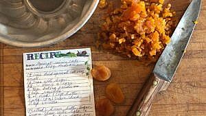 Chopped apricots next to a handwritten apricot raisin cake recipe