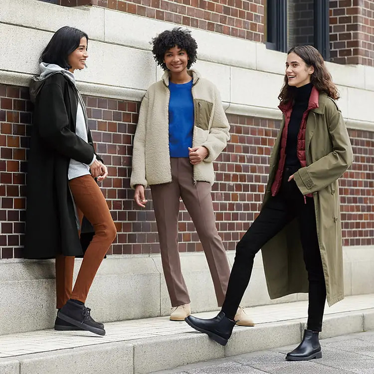 Three women wearing Heattech clothing chat on a sidewalk