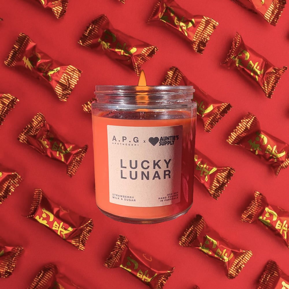 A red candle that says "Lucky Lunar" against a red background,