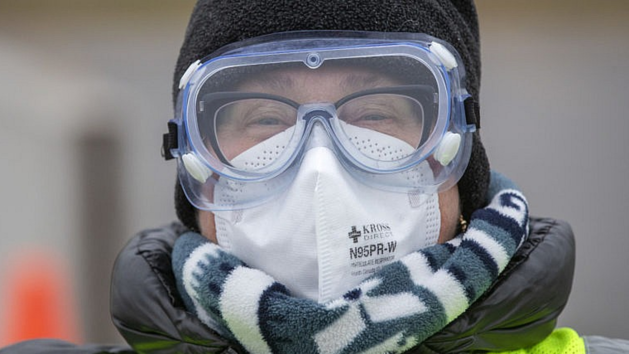 A doctor wears glasses, protective goggles and an N95 mask.