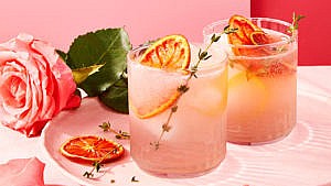 Two rose garden cocktails, garnished with dehydrated orange slices