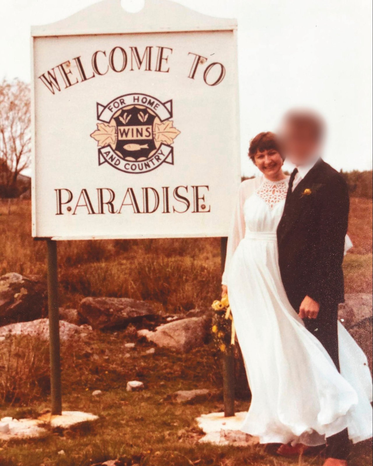 Anna Maria Tremonti poses with her ex-husband, Pat, on their wedding day in front of a "Welcome to Paradise" sign.