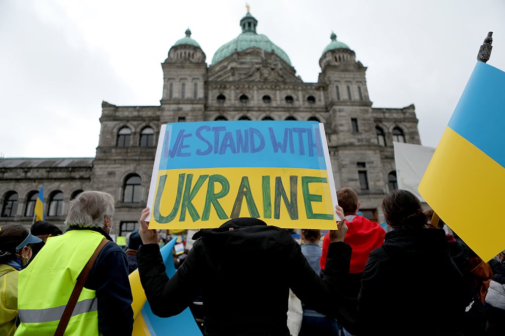 A poster painted like the Ukrainian flag reading "we stand with Ukraine" in front of the Victoria legislature at rally organized by the Ukrainian Canadian Congress on the steps of the B.C. Legislature in Victoria, Sunday, Feb. 27, 2022.