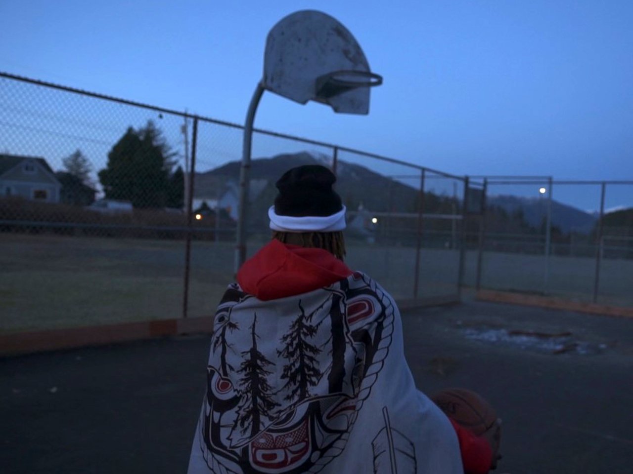 Josiah Wilson, donned in traditional garb, holds a basketball on the court.