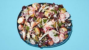 A salad with horseradish, trout and watercress on a blue plate on a blue table.
