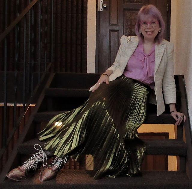 Sheila Wenham sits on a staircase wearing a thrifted outfit.