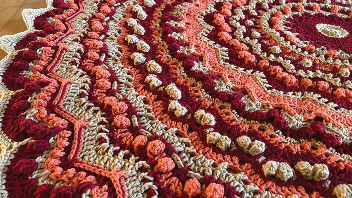 A close-up shot of a pink and red crocheted tree skirt