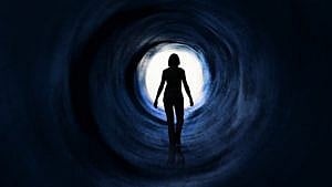 A woman in a dark tunnel walking towards the light