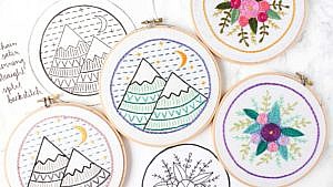 A collection of embroidery hoops, embroidered with mountains and flowers