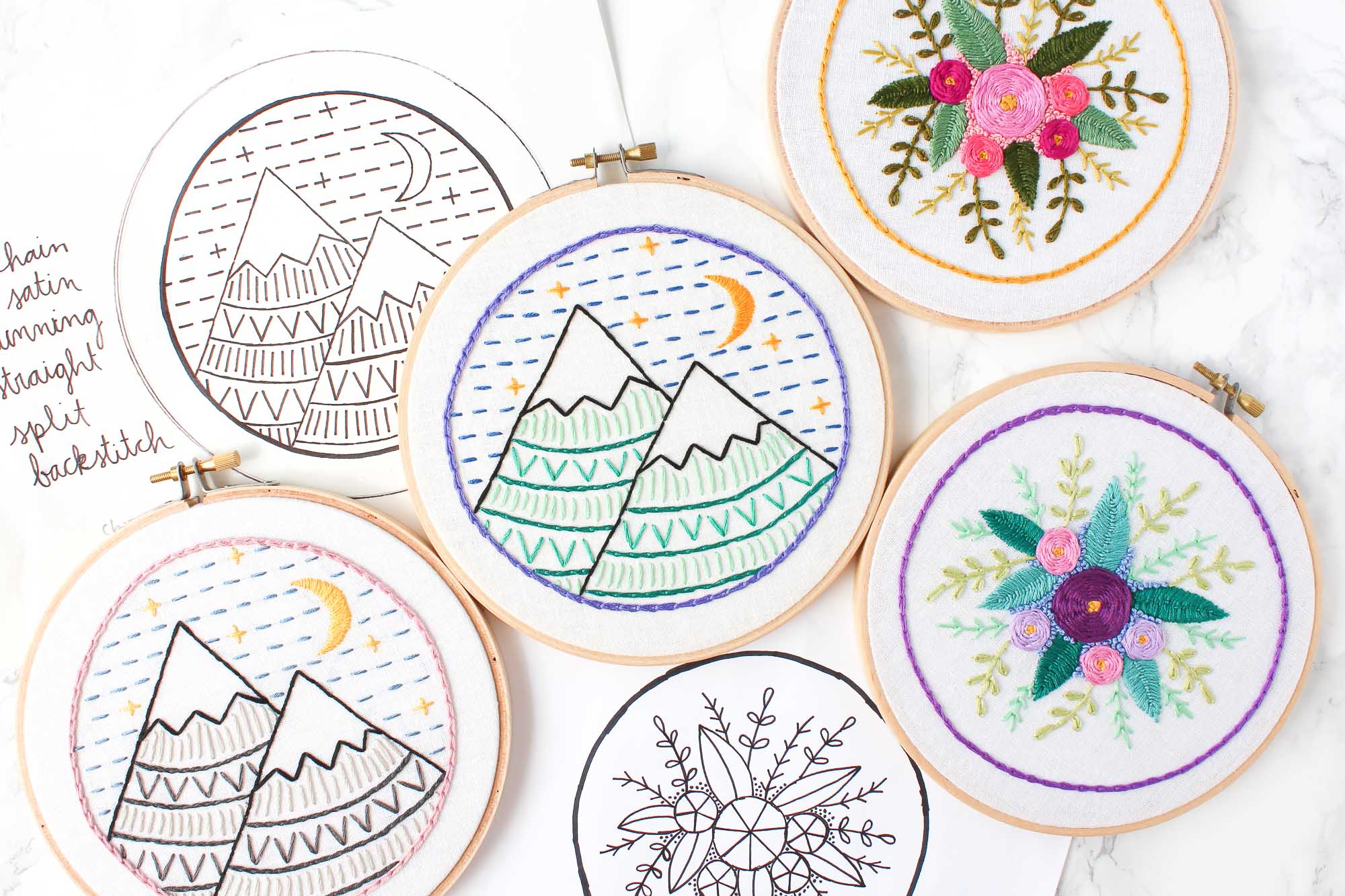 A collection of embroidery hoops, embroidered with mountains and flowers