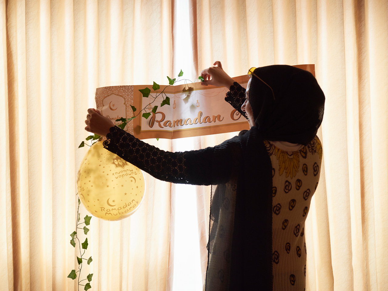 woman hangs up ramadan decorations at home