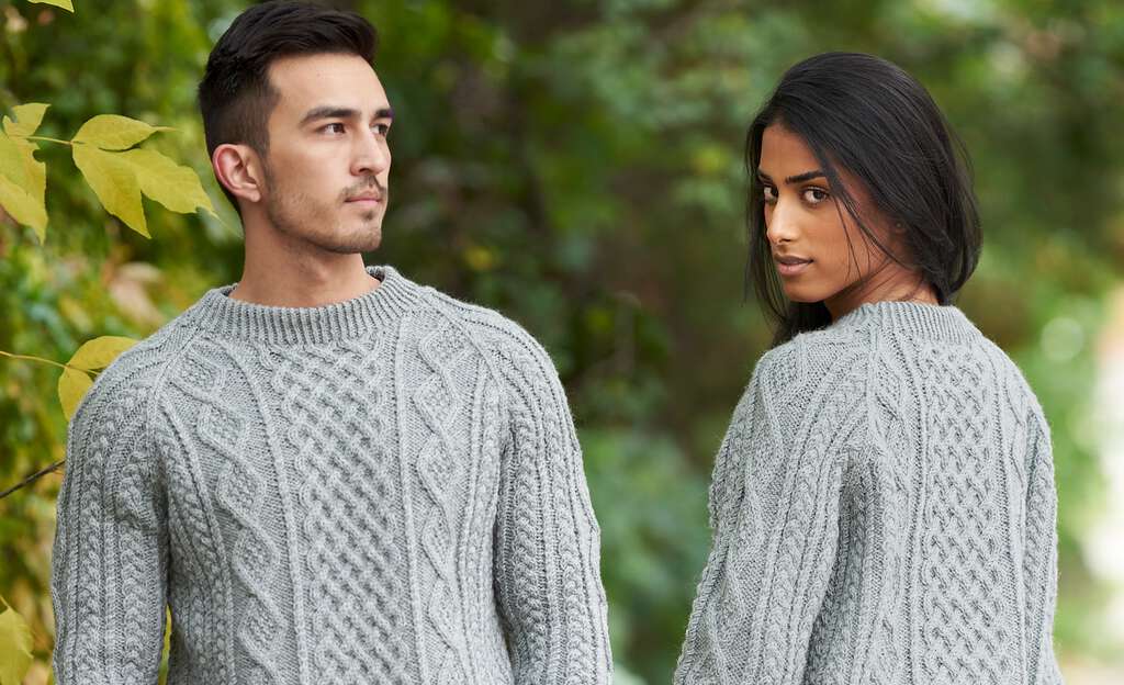 A man and woman outdoors wearing grey knit cardigans