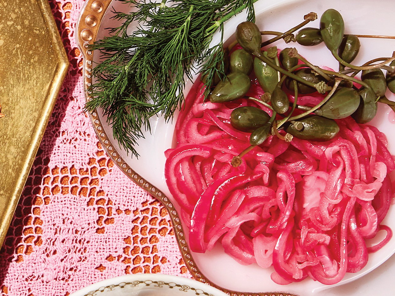 Pickled red onions served on a white platter atop a pink tablecloth