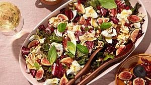 A fig and radicchio salad on a serving plate, surrounded by a sparkling beverage and a bowl of figs, for a feature on back-to-work lunch recipes