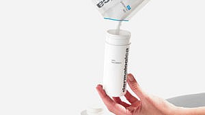 A model pouring Dermalogica Daily Microfoliant into a bottle from an eco-friendly pouch,