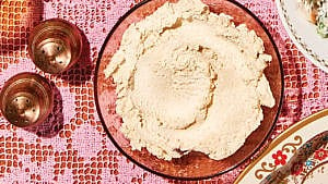 A bowl of cashew "cream cheese" served atop a pink lace tablecloth
