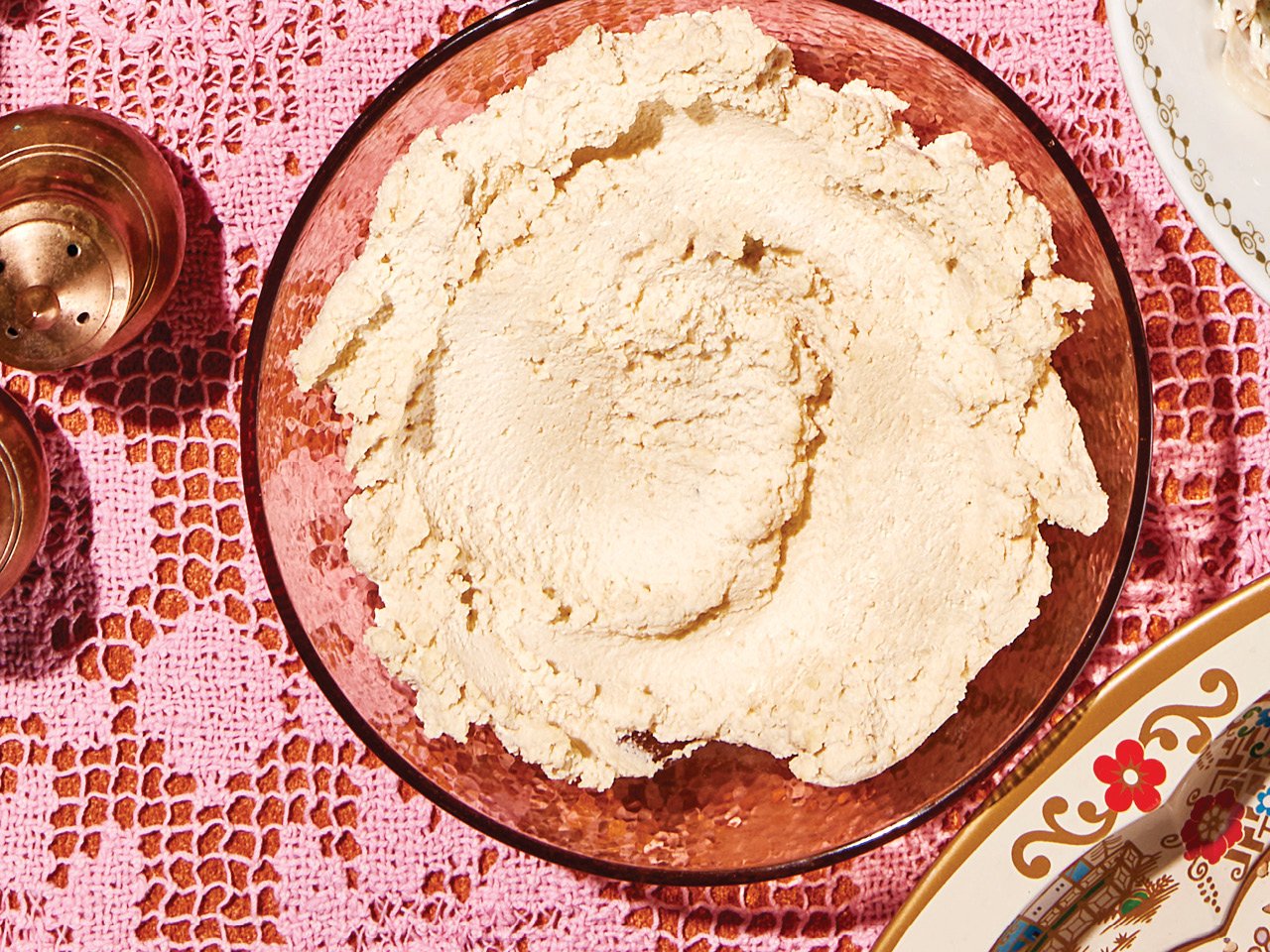 A bowl of cashew "cream cheese" served atop a pink lace tablecloth