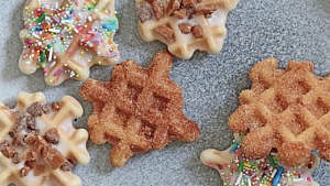 Churro waffle cookies topped with cinnamon, sugar, and sprinkles, served on a gray plate
