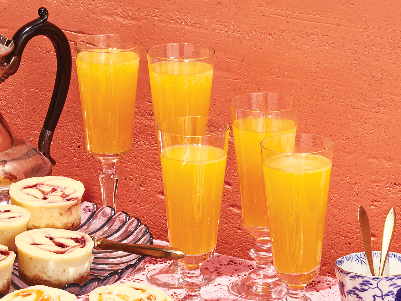 Five glasses of hard cider mimosa served on a table alongside a pitcher and bruch pastries