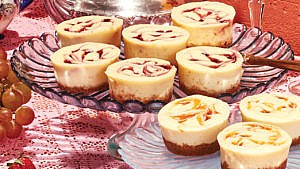 Several jam swirl mini cheesecakes on a serving dish laid on top of a pink lace tablecloth