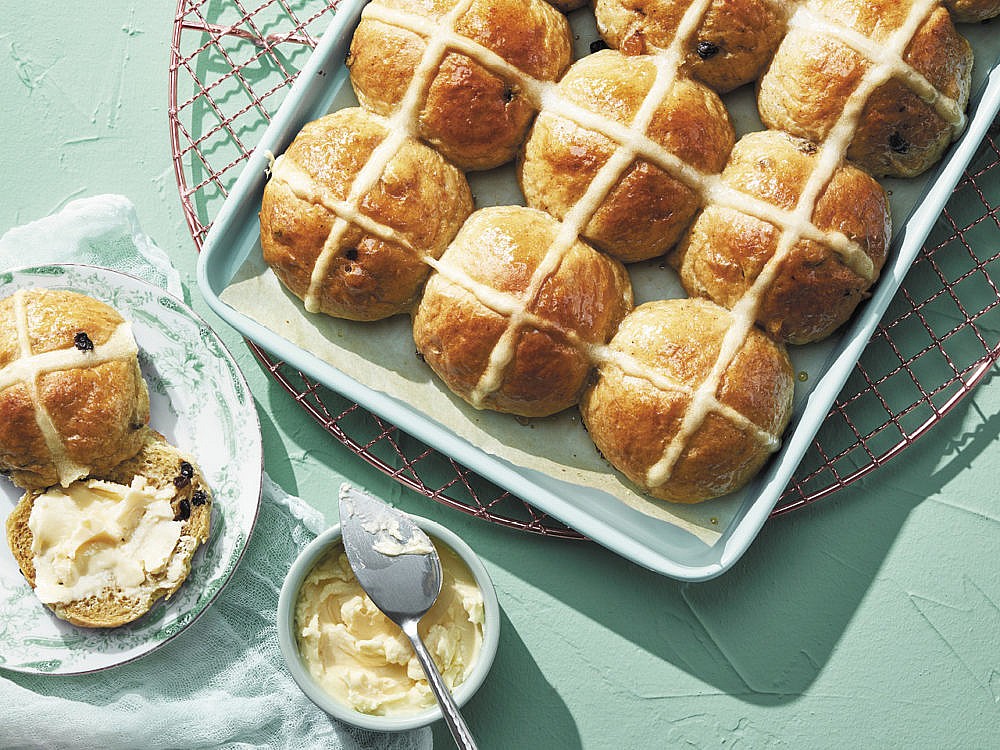 A tray of plant-based hot cross buns served on a turquoise table