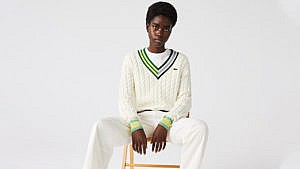 A model wears a preppy white cable-knit sweater from Lacoste