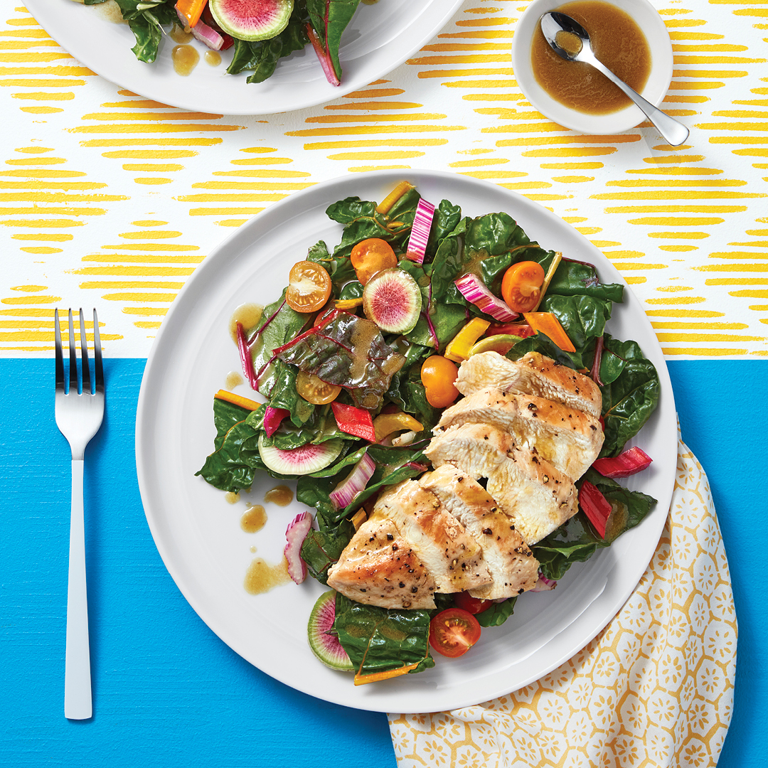 Grilled chicken with rainbow chard salad including tomatoes, and radish.