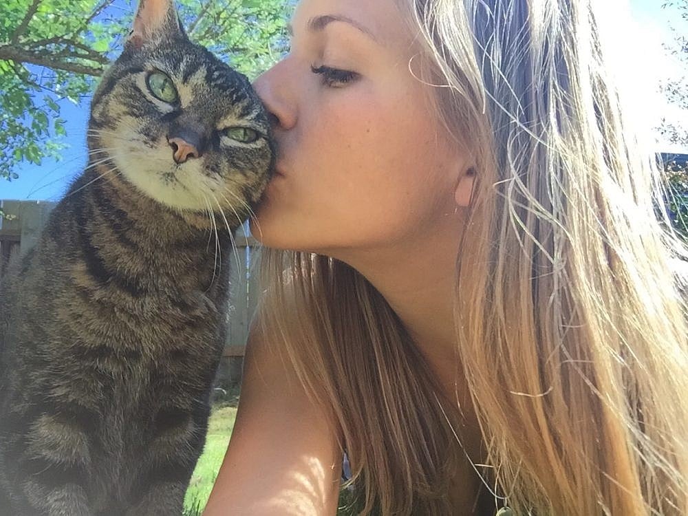 Women kissing her cat on its cheek