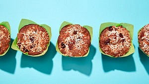 Three morning glory muffins with green wrappers and blue backdrop.