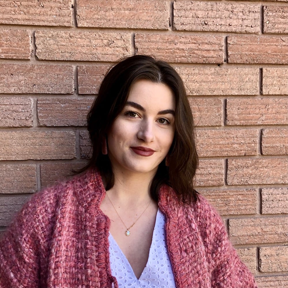 On reclaiming my body: a woman in dark lipstick smiling in front of a brick wall
