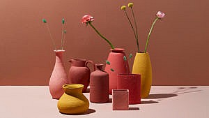 Several painted thrift store vases with flower stalks laid on a surface