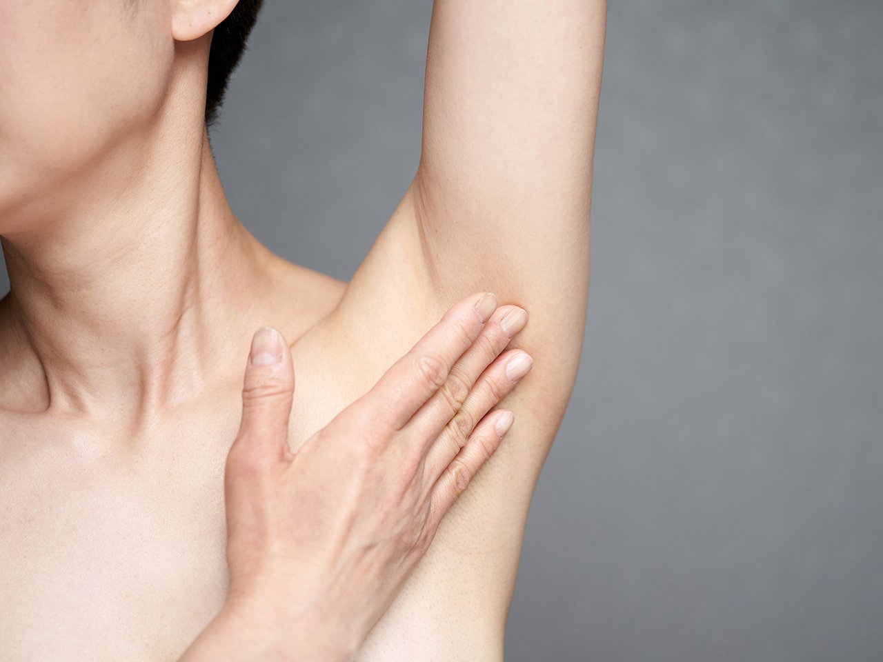 Woman lifting her arm and touching her armpit