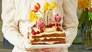 layered lemon poppyseed cake decoratd with rapsberries and tulips